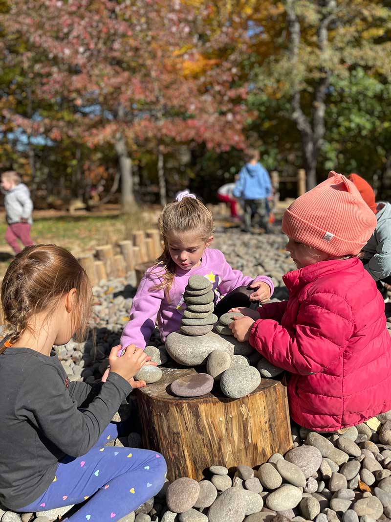 Girls stacking rocks on a log