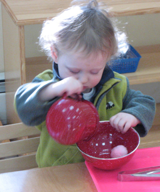 Toddler playing with toy cooking implements in a classroom