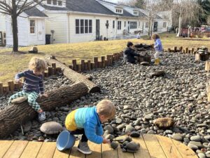 Kids playing in a mock riverbed with river rocks