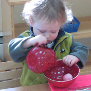 Toddler playing with toy cooking implements in a classroom